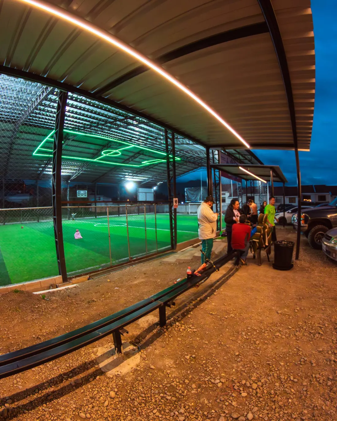 Banca junto a la cancha, con el campo de neón en el techo