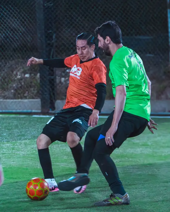 Jugador de naranja rematando ante un rival